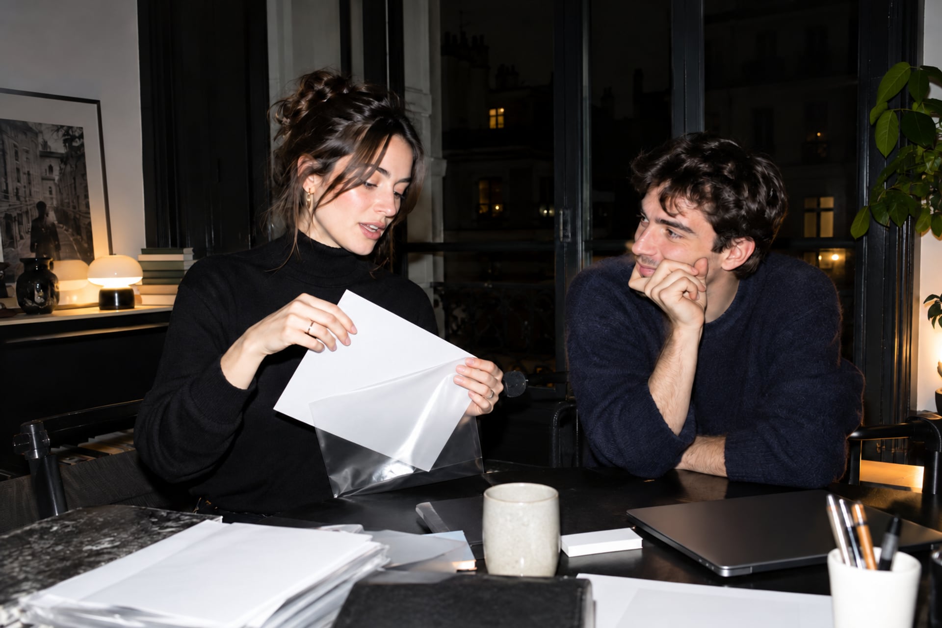 A writer files a blank sheet in a Paris workspace after dark.